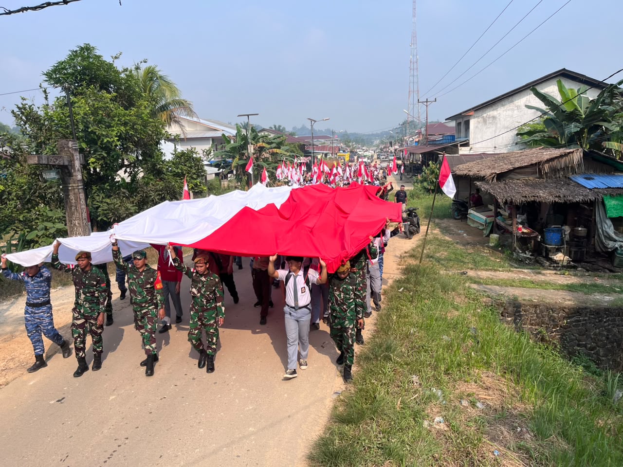 Mbminvestigasi.com | Satgas Pamtas RI-Malaysia Yonarmed 19/Bogani Bersama 500 Warga Kibarkan Bendera Merah Putih Raksasa di Perbatasan Jagoi Babang